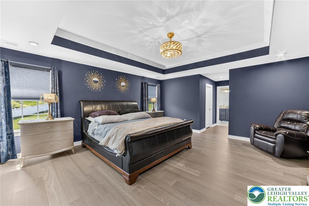 3952 Orth Street Bethlehem, PA 18020 - Photo 21 of 60 A tray ceiling with an elegant chandelier crowns this expansive primary bedroom featuring rich hardwood flooring.