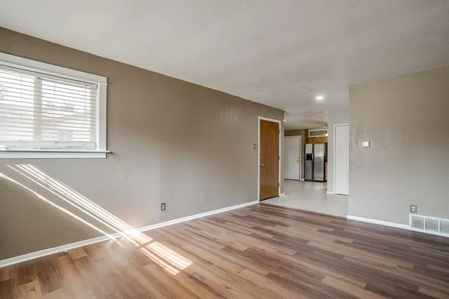 a view of an empty room with wooden floor and a window