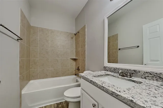 a bathroom with a granite countertop sink a toilet and bathtub