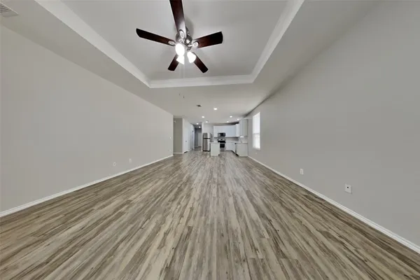 a view of empty room with wooden floor and ceiling fan