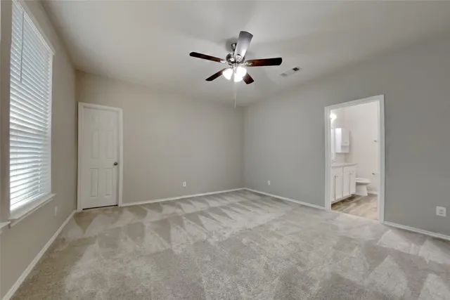 an empty room with windows and fan