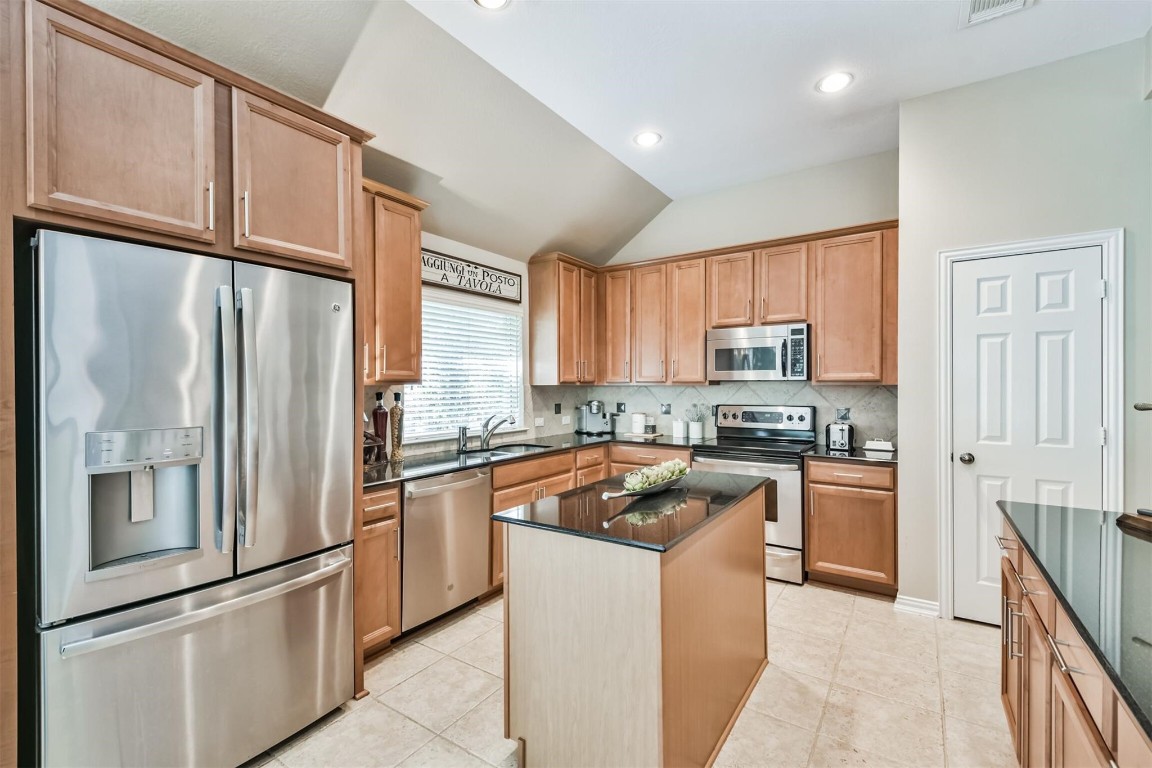 12711 Big Spring Trail Humble, TX 77346 - Photo 10 of 25 a kitchen with stainless steel appliances granite countertop a refrigerator a sink a stove and white cabinets
