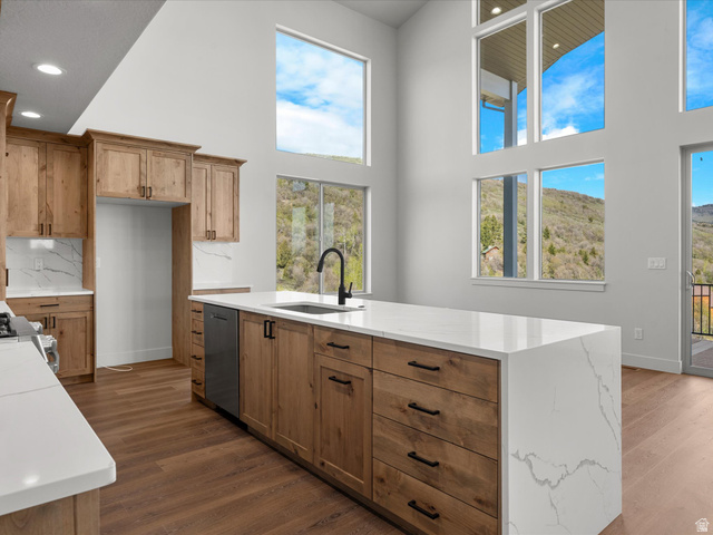 1159 North Broad Hollow Road Garden City, UT 84028 - Photo 31 of 55 Open-concept kitchen featuring extensive wood cabinetry, a large waterfall island with a sink and a black faucet, white countertops with veining, and wood-finish flooring