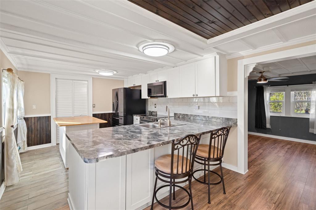 7288 Coventry Court Weeki Wachee, FL 34607 - Photo 34 of 82 a kitchen with granite countertop a table chairs microwave and cabinets