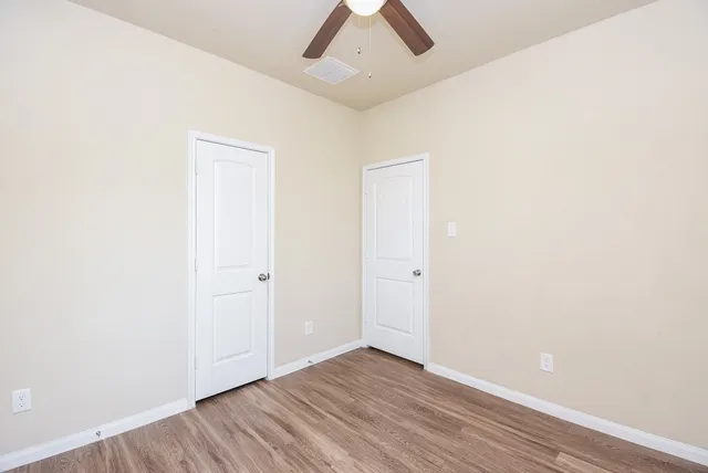 an empty room with wooden floor and fan