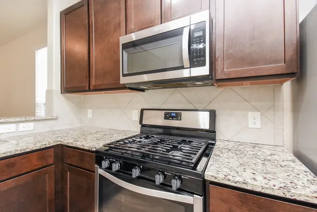 a kitchen with stainless steel appliances granite countertop a stove and a microwave