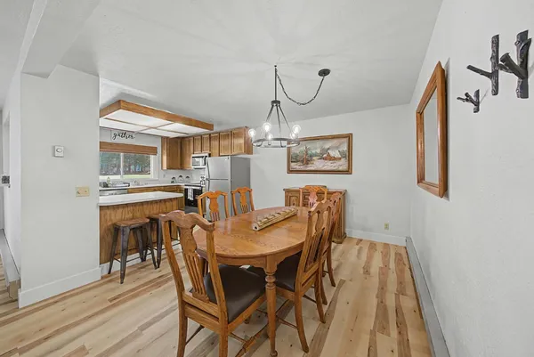 a open kitchen with stainless steel appliances granite countertop a table chairs and a refrigerator