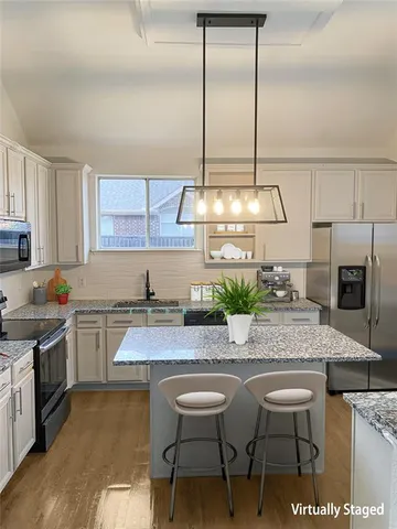a kitchen with stainless steel appliances granite countertop a sink a stove and a wooden cabinets
