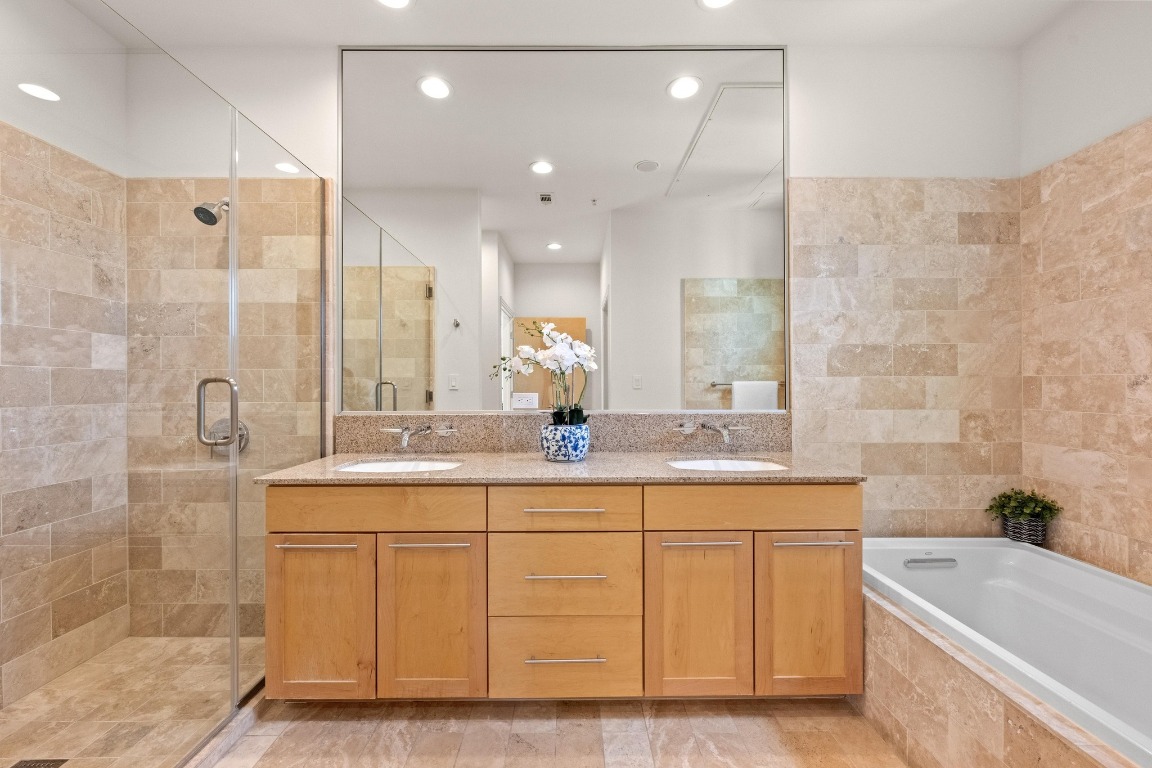 1600 Barton Springs Road, Unit 5601 Austin, TX 78704 - Photo 19 of 36 a bathroom with a double vanity sink a mirror and a bathtub