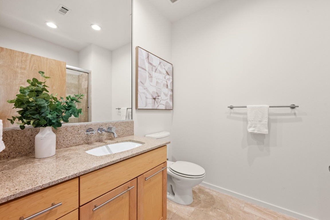 1600 Barton Springs Road, Unit 5601 Austin, TX 78704 - Photo 23 of 36 a bathroom with a granite countertop sink a toilet and a mirror