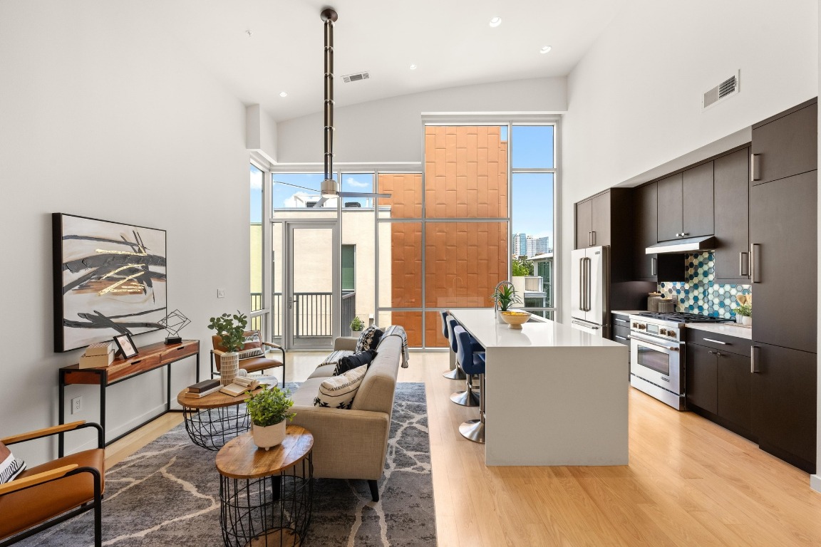 1600 Barton Springs Road, Unit 5601 Austin, TX 78704 - Photo 4 of 36 a living room with stainless steel appliances kitchen island granite countertop a table chairs and a refrigerator