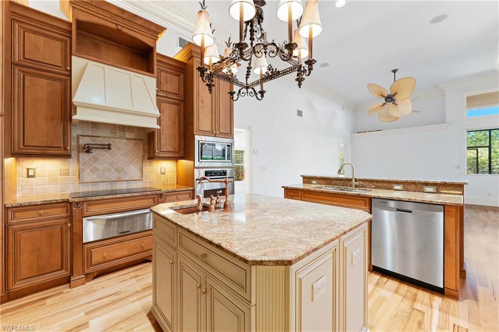 7126 Mill Run Road Naples, FL 34109 - Photo 11 of 49 Kitchen featuring sink, premium range hood, an island with sink, pendant lighting, and appliances with stainless steel finishes