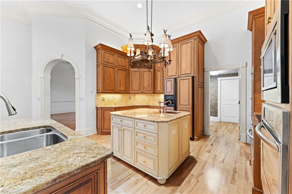 7126 Mill Run Road Naples, FL 34109 - Photo 13 of 49 Kitchen with pendant lighting, sink, light stone countertops, an island with sink, and appliances with stainless steel finishes