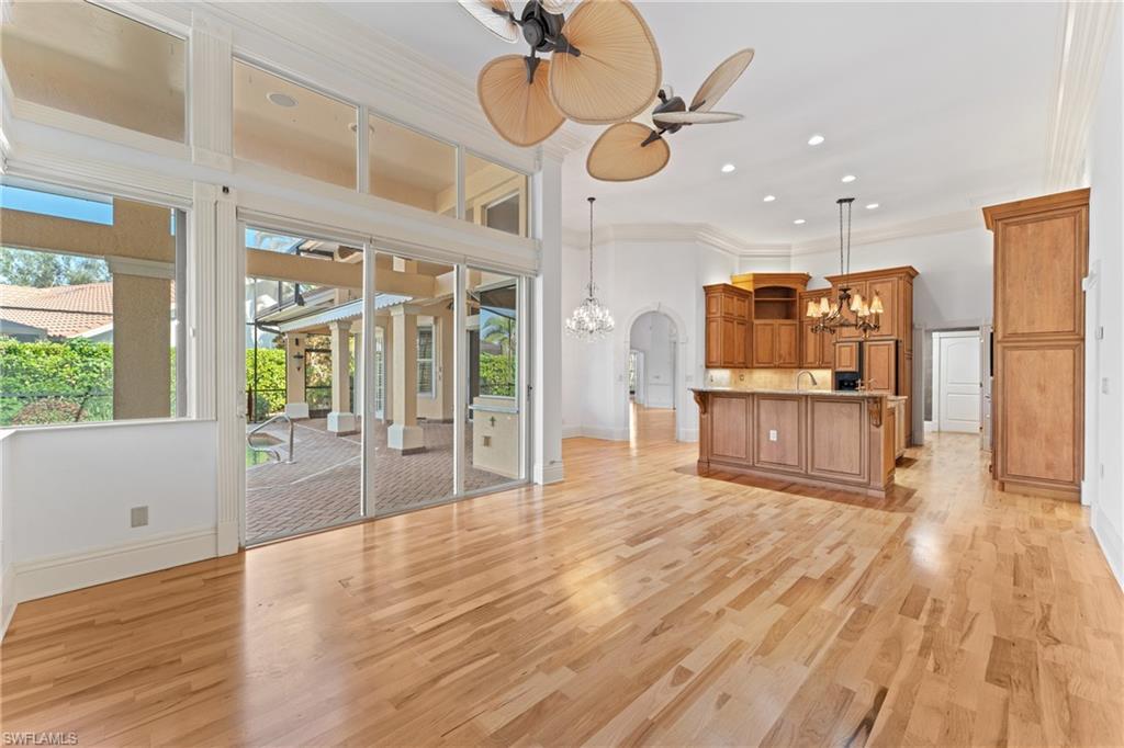7126 Mill Run Road Naples, FL 34109 - Photo 14 of 49 Unfurnished living room with crown molding, ceiling fan with notable chandelier, and light wood-type flooring