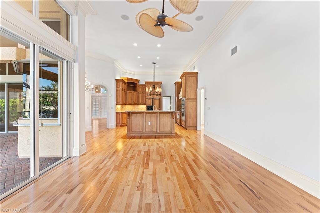 7126 Mill Run Road Naples, FL 34109 - Photo 15 of 49 Unfurnished living room featuring ceiling fan with notable chandelier, ornamental molding, and a towering ceiling