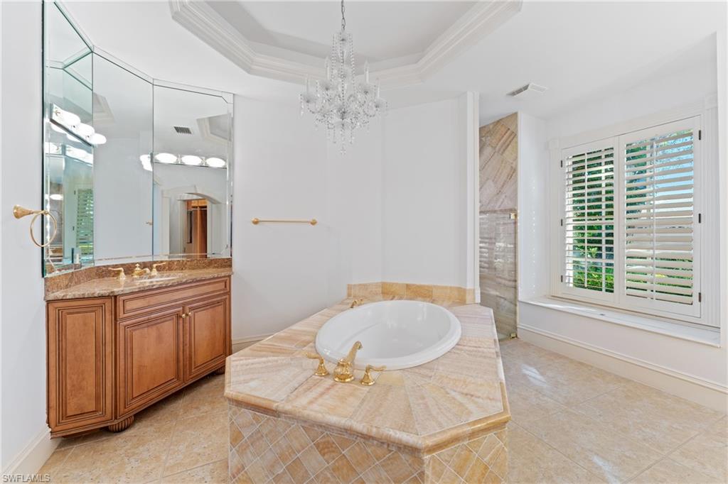 7126 Mill Run Road Naples, FL 34109 - Photo 17 of 49 Bathroom featuring a raised ceiling, crown molding, a chandelier, shower with separate bathtub, and vanity