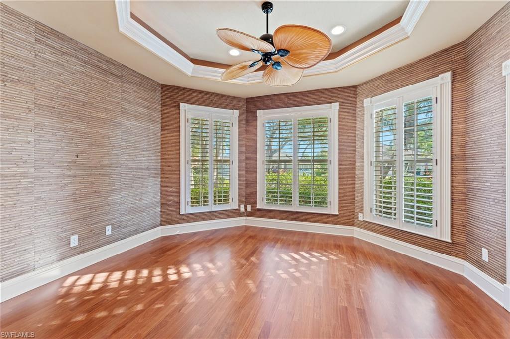 7126 Mill Run Road Naples, FL 34109 - Photo 21 of 49 Unfurnished room with ceiling fan, a raised ceiling, ornamental molding, and wood-type flooring