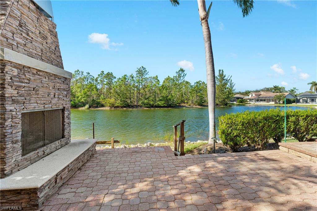 7126 Mill Run Road Naples, FL 34109 - Photo 40 of 49 View of patio / terrace with a water view and an outdoor stone fireplace
