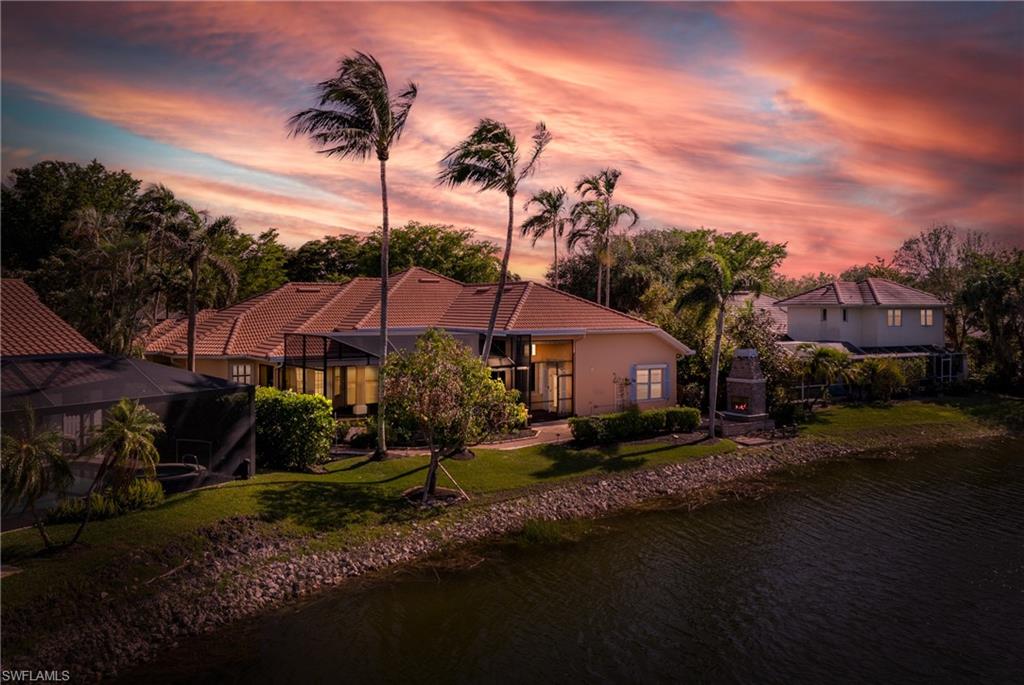 7126 Mill Run Road Naples, FL 34109 - Photo 44 of 49 Back house at sunset featuring a lawn, glass enclosure, and a water view