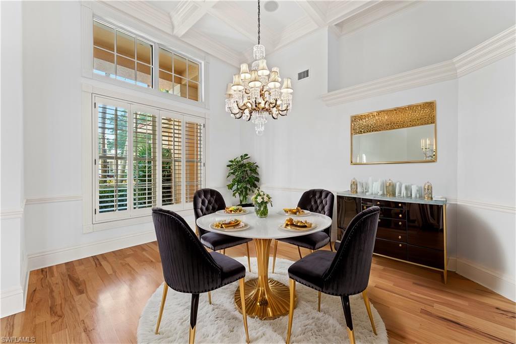 7126 Mill Run Road Naples, FL 34109 - Photo 5 of 49 Dining area with coffered ceiling, crown molding, beamed ceiling, a notable chandelier, and wood-type flooring