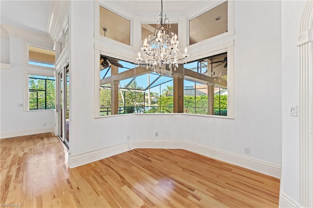 7126 Mill Run Road Naples, FL 34109 - Photo 7 of 49 Unfurnished room featuring hardwood / wood-style flooring, crown molding, and an inviting chandelier