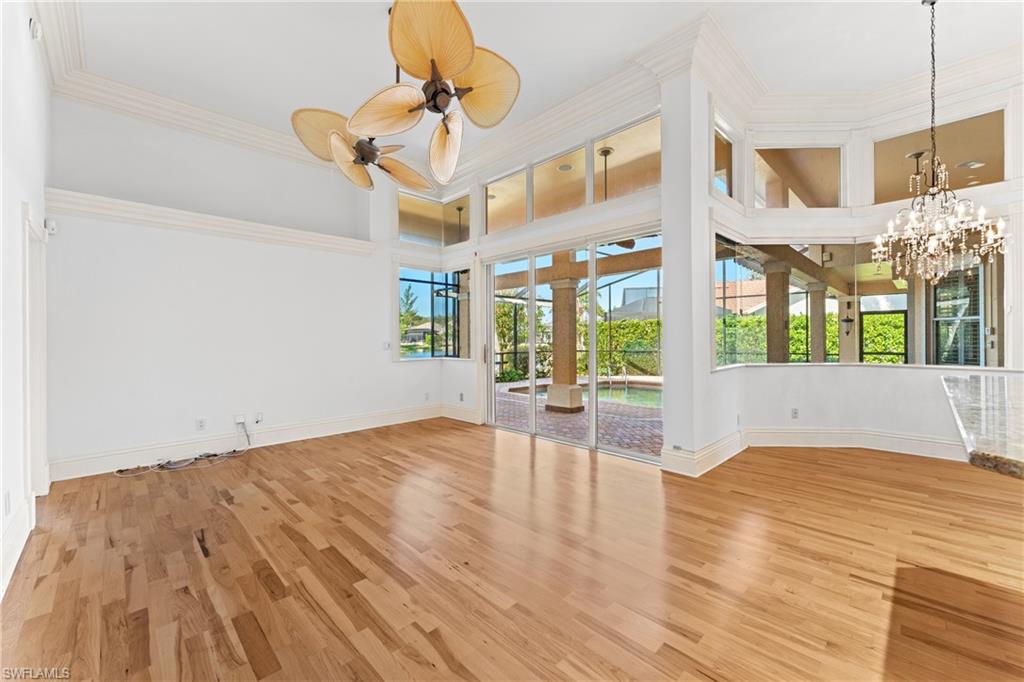 7126 Mill Run Road Naples, FL 34109 - Photo 8 of 49 Spare room with hardwood / wood-style flooring, ceiling fan with notable chandelier, crown molding, and a high ceiling