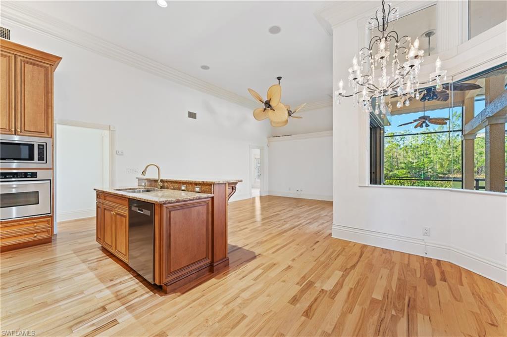 7126 Mill Run Road Naples, FL 34109 - Photo 9 of 49 Kitchen with ceiling fan with notable chandelier, stainless steel appliances, sink, hanging light fixtures, and an island with sink