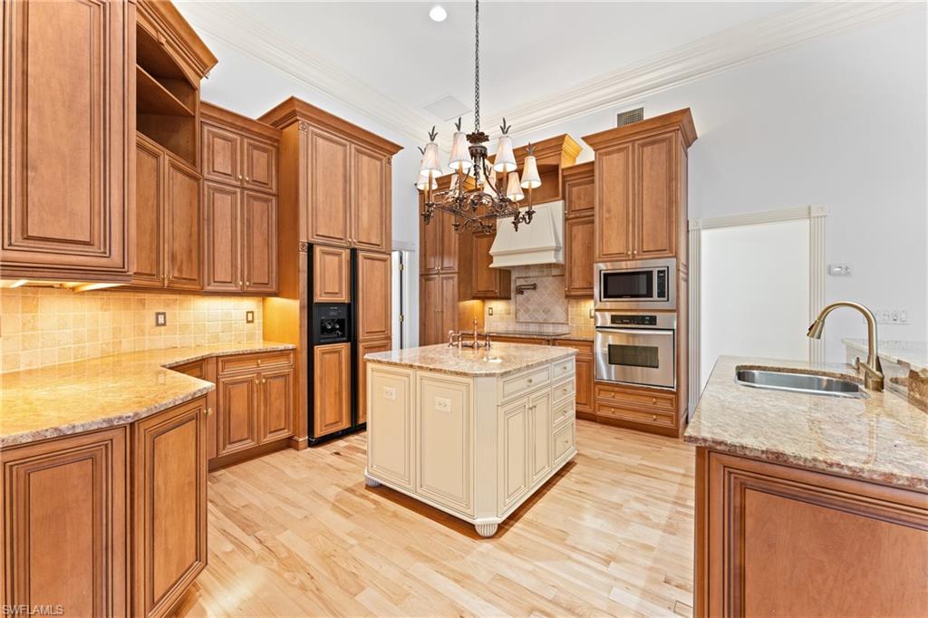 7126 Mill Run Road Naples, FL 34109 - Photo 10 of 49 Kitchen with sink, hanging light fixtures, light stone counters, a center island with sink, and appliances with stainless steel finishes