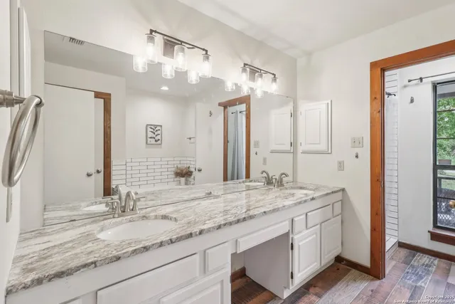 a bathroom with a granite countertop double vanity sink and a mirror