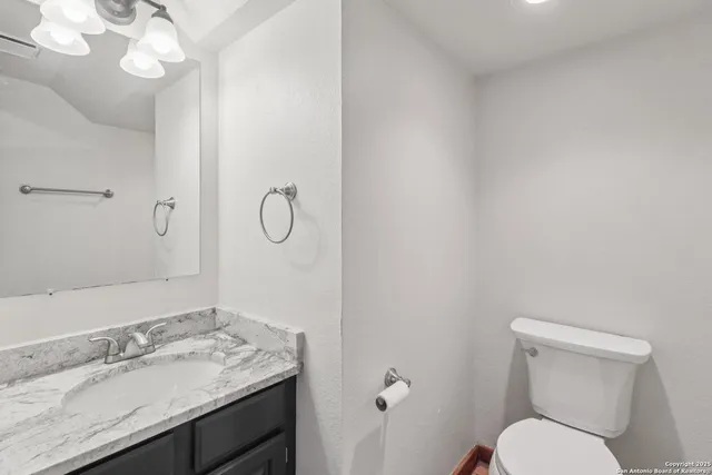a bathroom with a granite countertop toilet sink and mirror