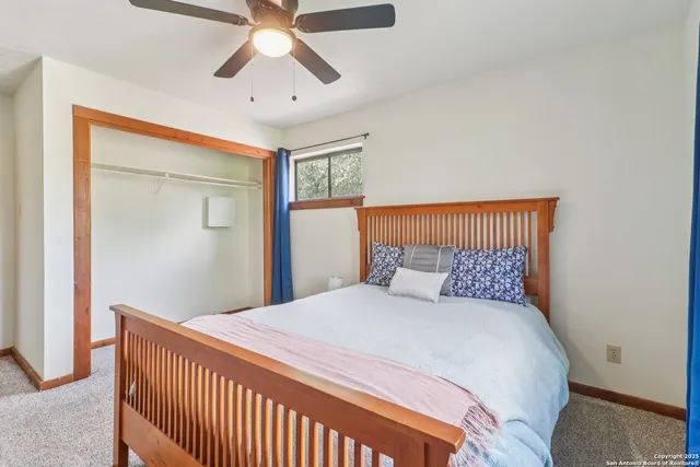 a bedroom with a large bed and a chandelier fan
