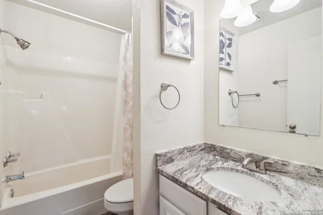 a bathroom with a granite countertop sink toilet and shower