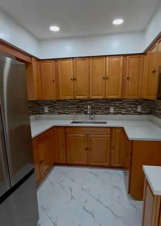 a kitchen with stainless steel appliances granite countertop a refrigerator a sink dishwasher with wooden cabinets and a chair