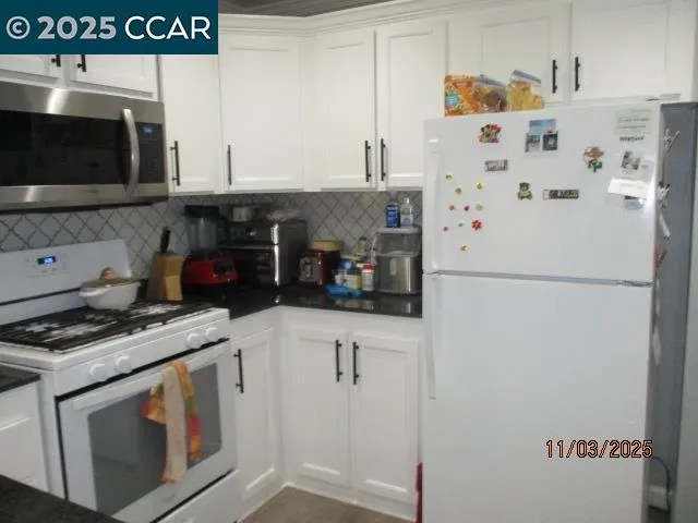 a kitchen with stainless steel appliances a refrigerator a stove and white cabinets