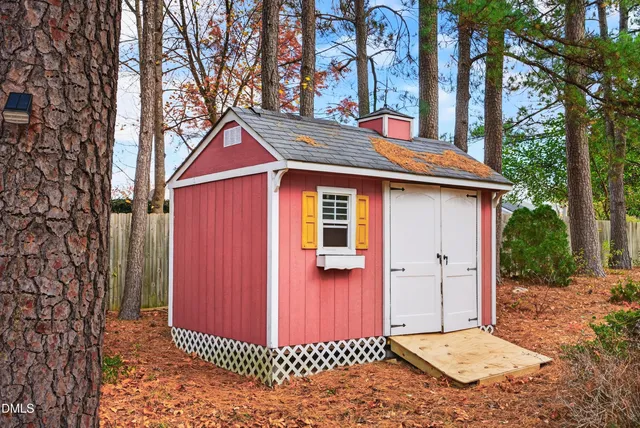 a view of a backyard with large trees and wooden fence