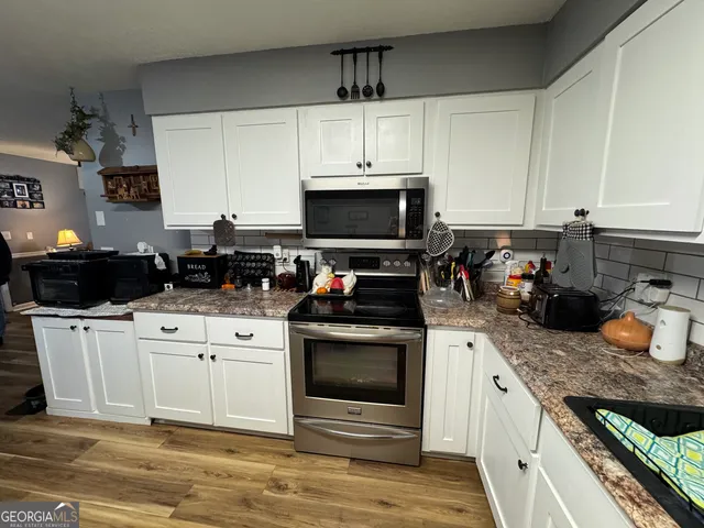 a kitchen with stainless steel appliances granite countertop a stove a sink and a microwave