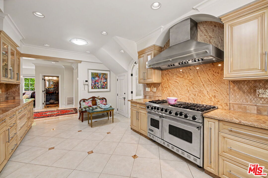 204 Foothill Road Beverly Hills, CA 90210 - Photo 10 of 38 a kitchen with stainless steel appliances a stove a chimney and a refrigerator
