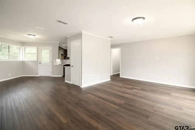 a view of empty room with wooden floor and window