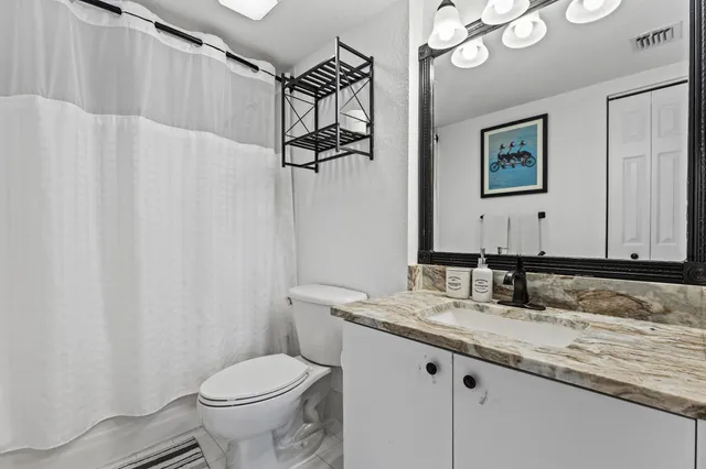 a bathroom with a granite countertop sink mirror vanity and toilet