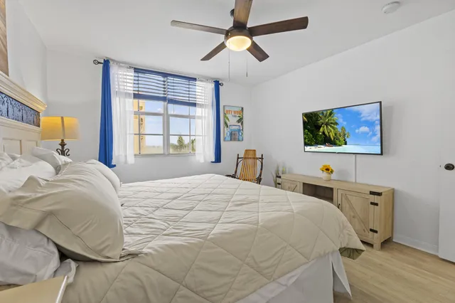 a bedroom with a bed a dresser and potted plant