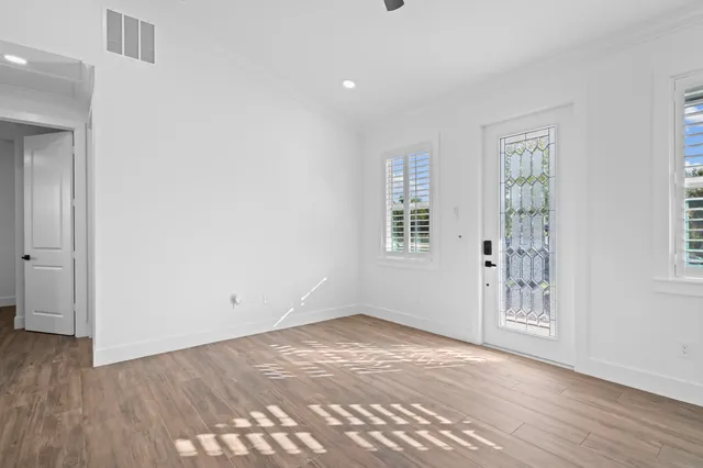 a view of kitchen and empty room with wooden floor