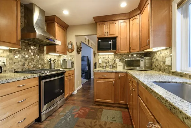 a kitchen with stainless steel appliances kitchen island granite countertop a sink counter space cabinets and a large window