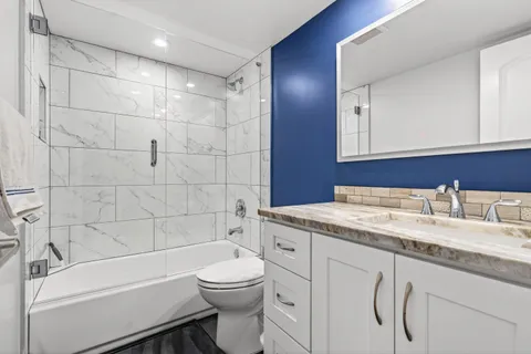 a bathroom with a granite countertop toilet sink and mirror