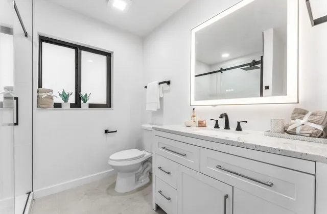 a bathroom with a granite countertop toilet sink mirror and window