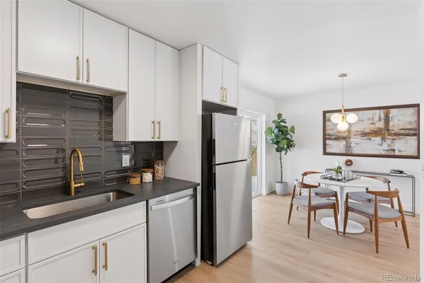 a kitchen with a refrigerator a stove a sink and white cabinets with wooden floor