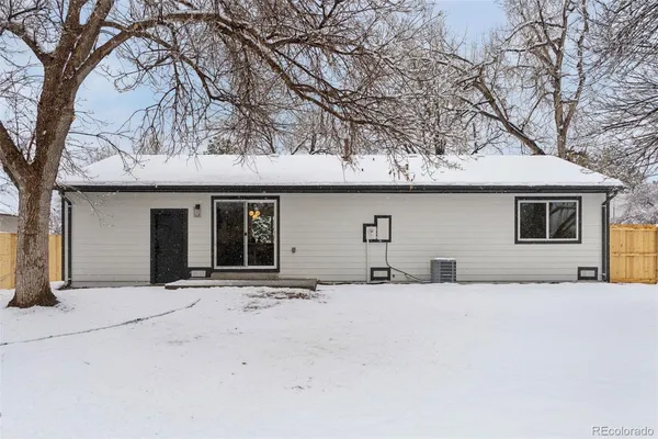 front view of a house with a yard covered with snow