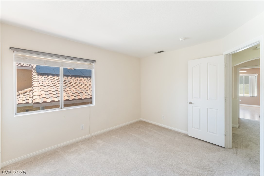 8872 Chapman Point Las Vegas, NV 89129 - Photo 18 of 29 A well-proportioned bedroom offers serene views through a generously sized window, creating a tranquil retreat.