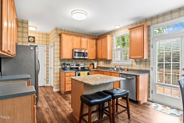 a kitchen with stainless steel appliances granite countertop sink refrigerator table and chairs