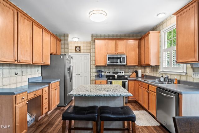 a kitchen with stainless steel appliances granite countertop a stove top oven a sink dishwasher a dining table and chairs with wooden floor