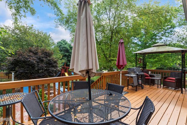 a view of a patio with a dining table and chairs with wooden floor and fence